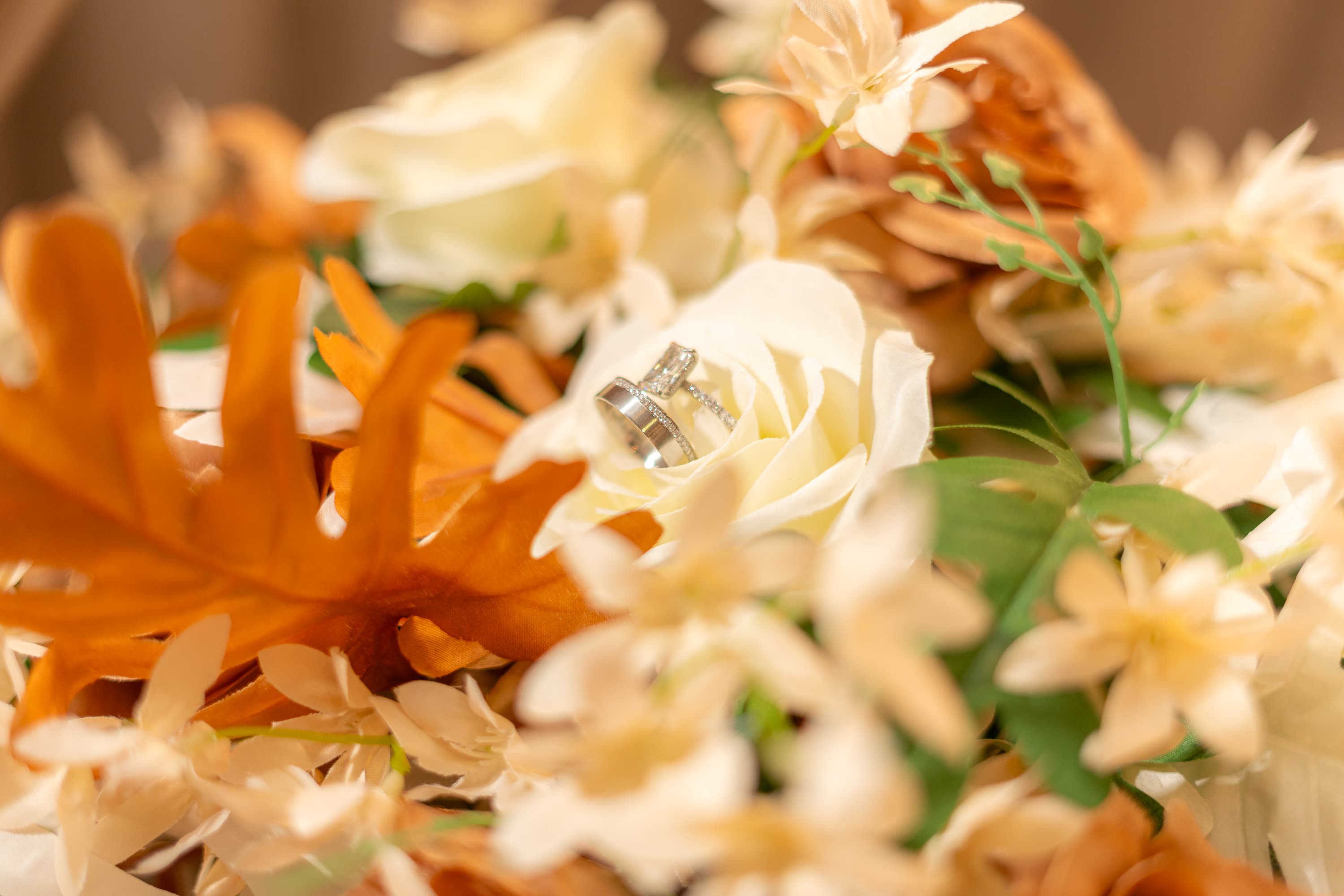 Wedding rings arranged inside cream and amber flowers.