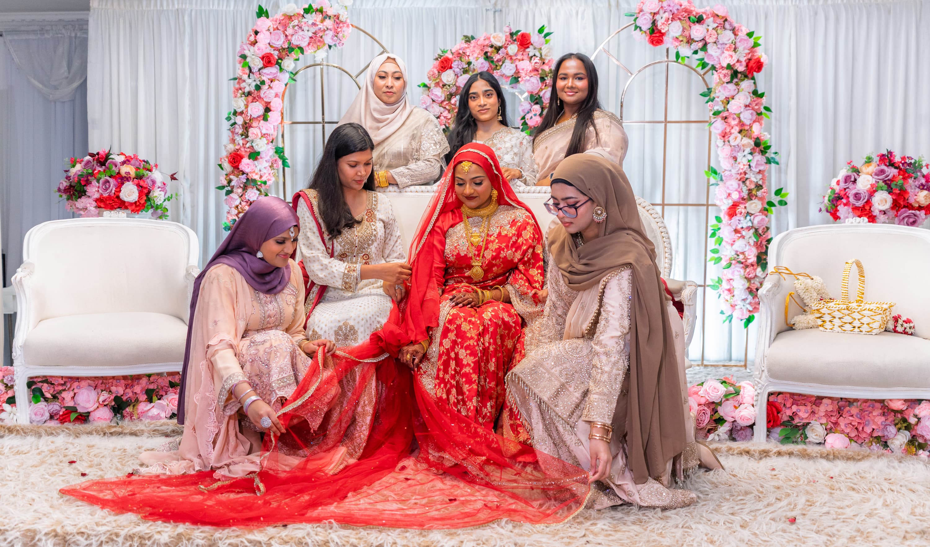 Bride standing with family and friends on a decorated wedding stage.